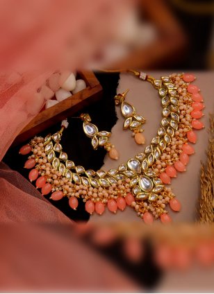 This designer Peach Necklace Set detailed with Kundan